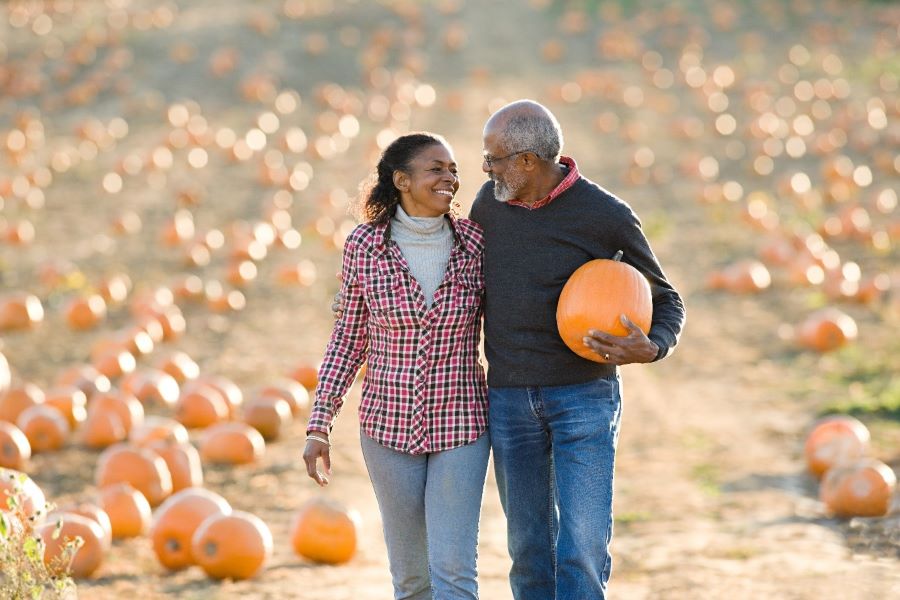 A happy couple walking in pumpkin patch