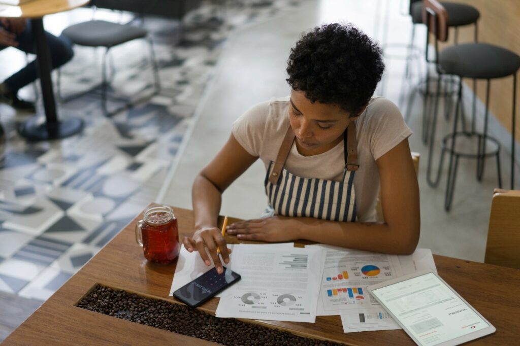 A young woman sits at a table with financial statements and a calculator